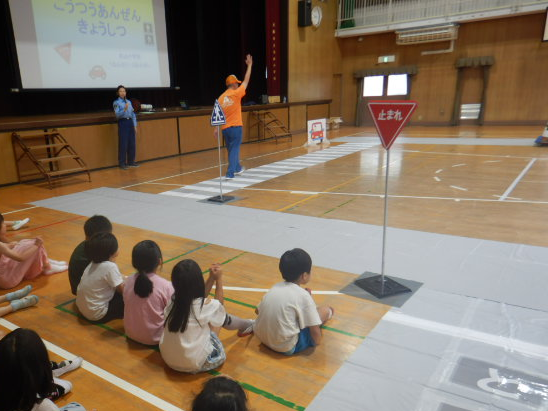 講堂に設置した模擬道路上を安全に歩く見本を見せる区役所職員