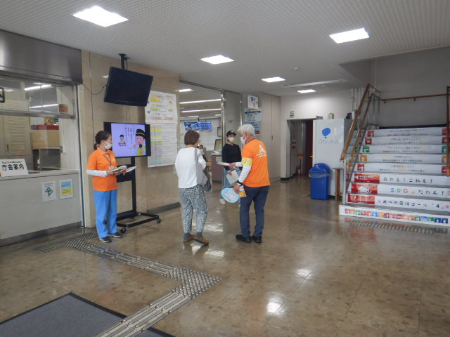 来庁者に啓発物品を配付して注意喚起する区役所職員