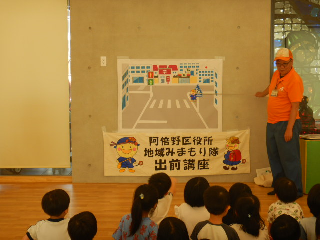 横断歩道の絵図を使って安全なわたり方を説明する区役所職員