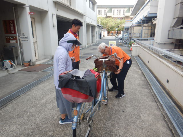自転車の前かごにひったくり防止カバーを取りつける区役所職員