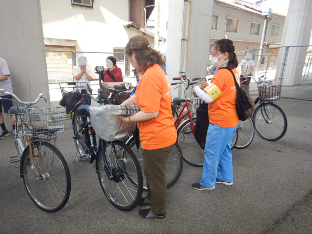 キャンペーン参加者の自転車前かごに啓発物品を配付する区役所職員