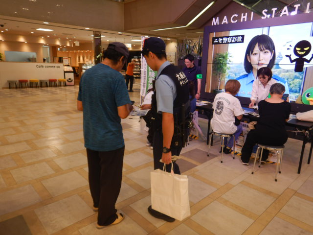 近鉄百貨店8階三井住友銀行前フロアーで警察官が特殊詐欺被害防止を呼びかける
