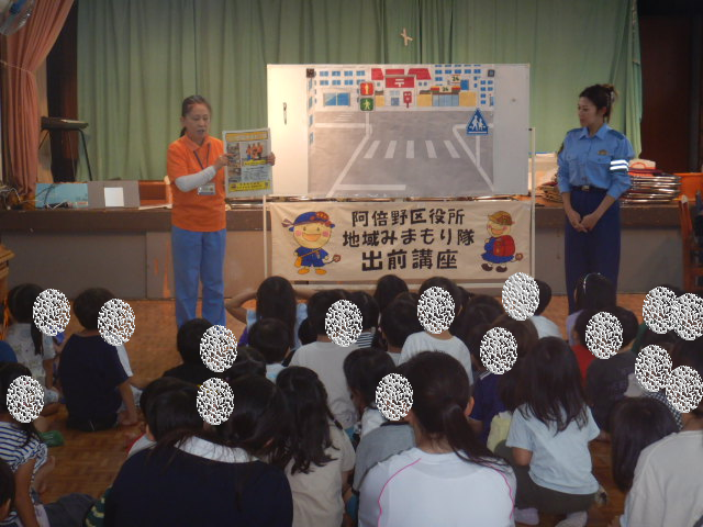 地域みまもり隊のポスターを見せながら園児に自己紹介する