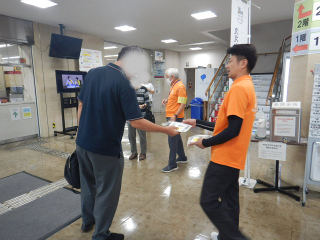 来庁者に啓発物品を配付し特殊詐欺被害防止を呼びかける区役所職員