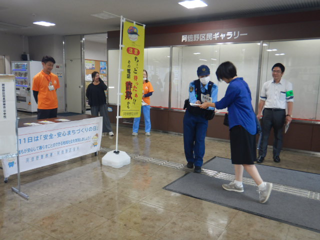 区役所玄関ロビーで来庁者に注意喚起する警察官と区役所職員