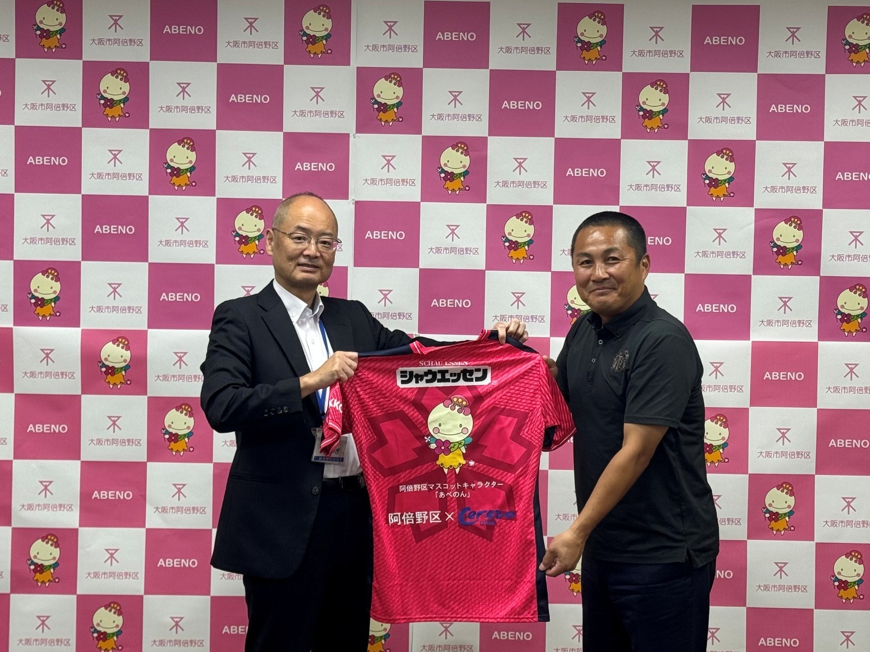 青柳区長、森島会長がユニフォームを持っている様子