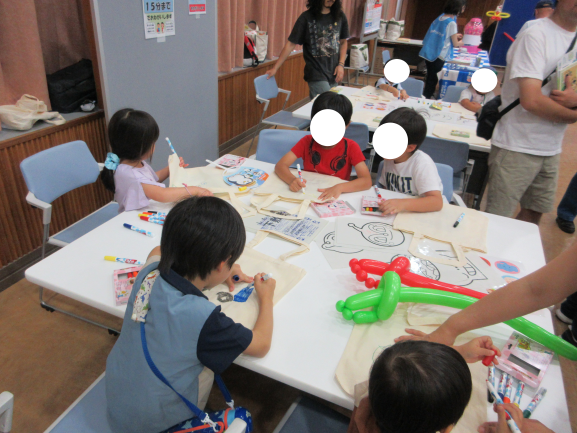 子どもたちがエコバッグに絵を描いている写真