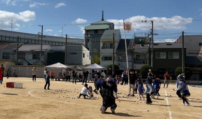 高い位置にカゴがあり、頑張って玉を投げる子どもたち