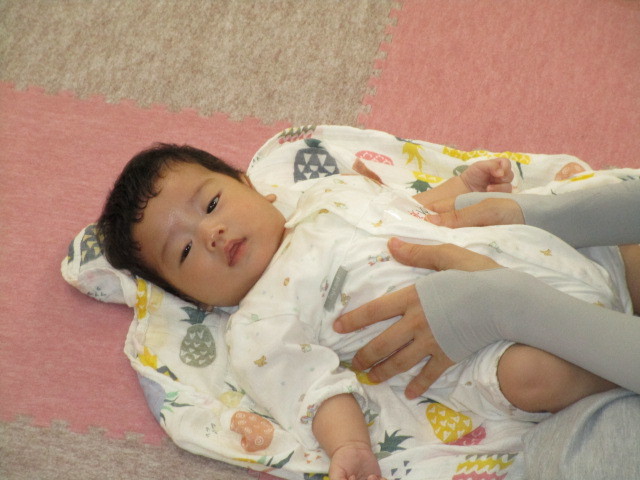 お母さんにふれあいあそびをしてもらい気持ち良さそうな表情の赤ちゃんの写真