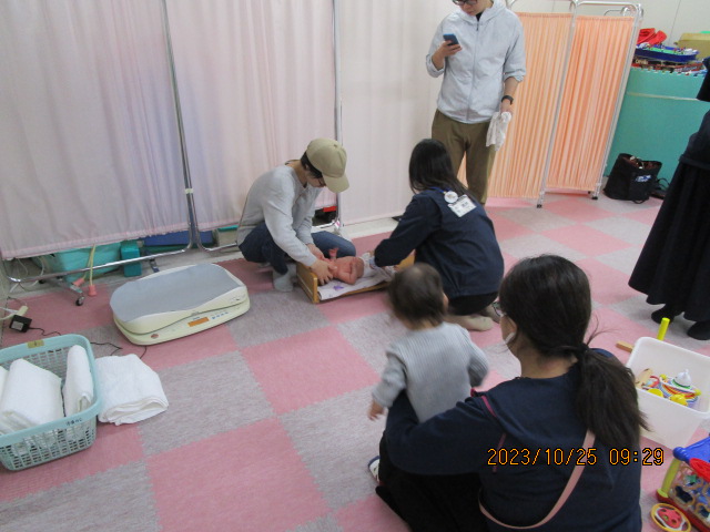 保健師に身長を測ってもらっている赤ちゃんの写真