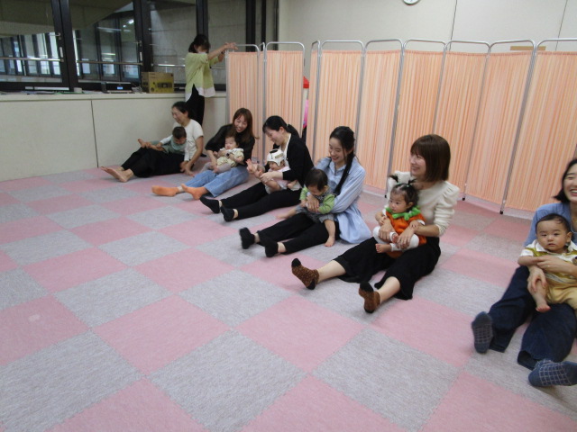 保護者がお子さんを抱っこしてお尻歩き競争をしている様子