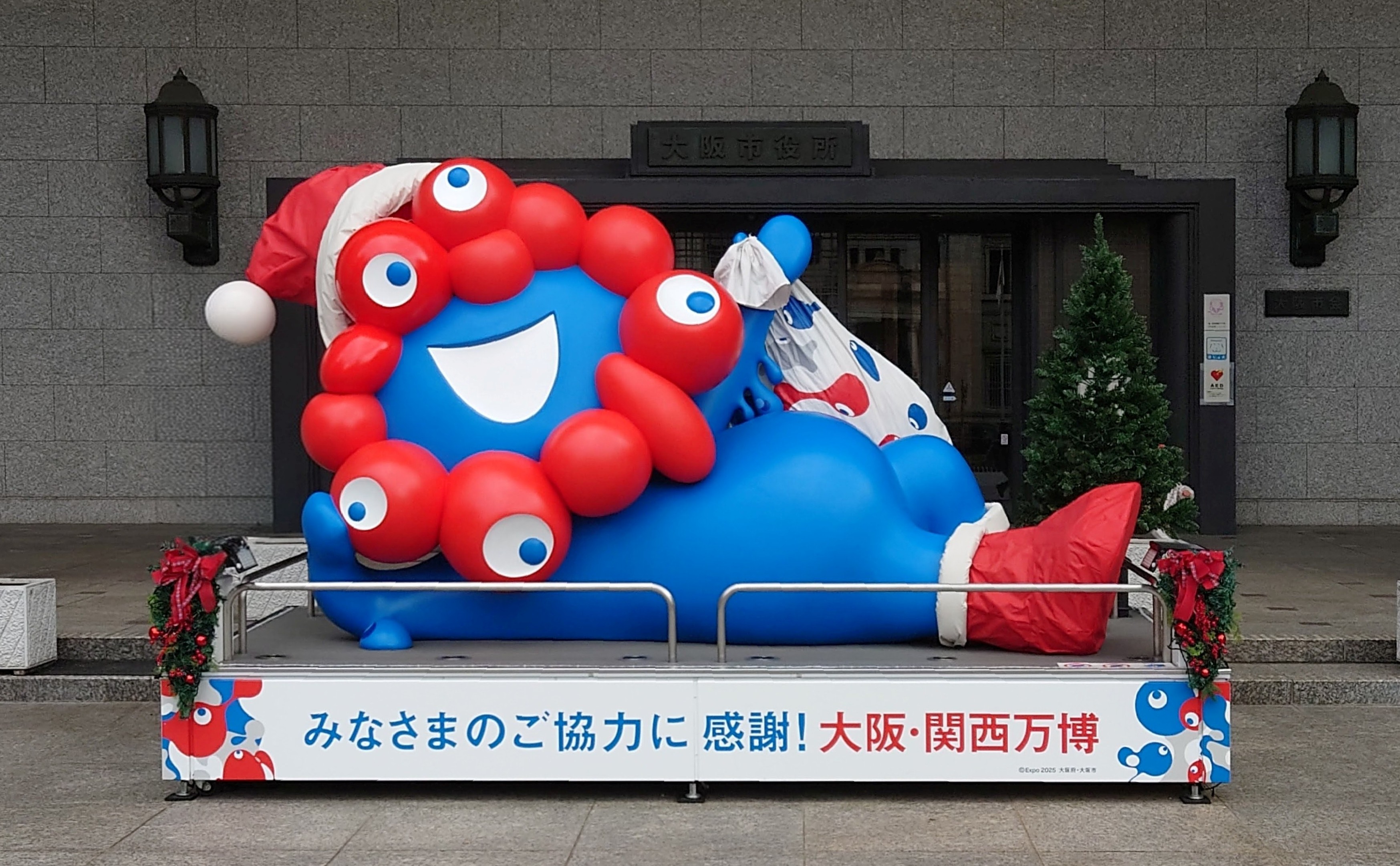 大阪市役所正面玄関前のミャクミャクモニュメント「ねそべり」（サンタクロース）