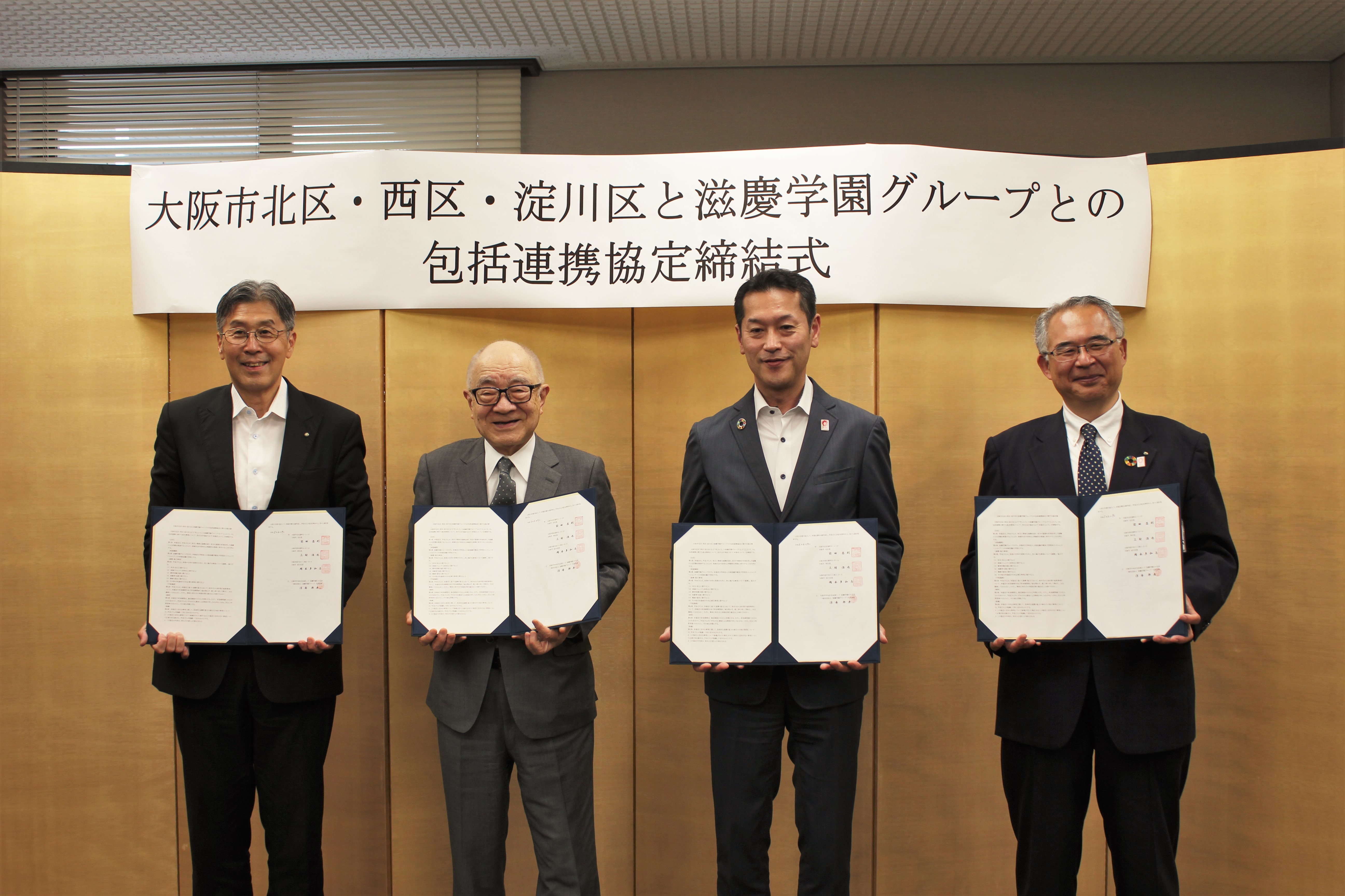 左から前田北区長、浮舟代表理事、三村西区長、岡本淀川区長が協定書を手に持って並ぶ