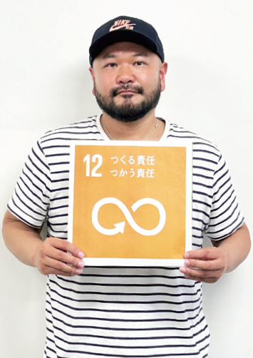 代表の安藤育敏さんがSDGsの12番のボードを持っている写真