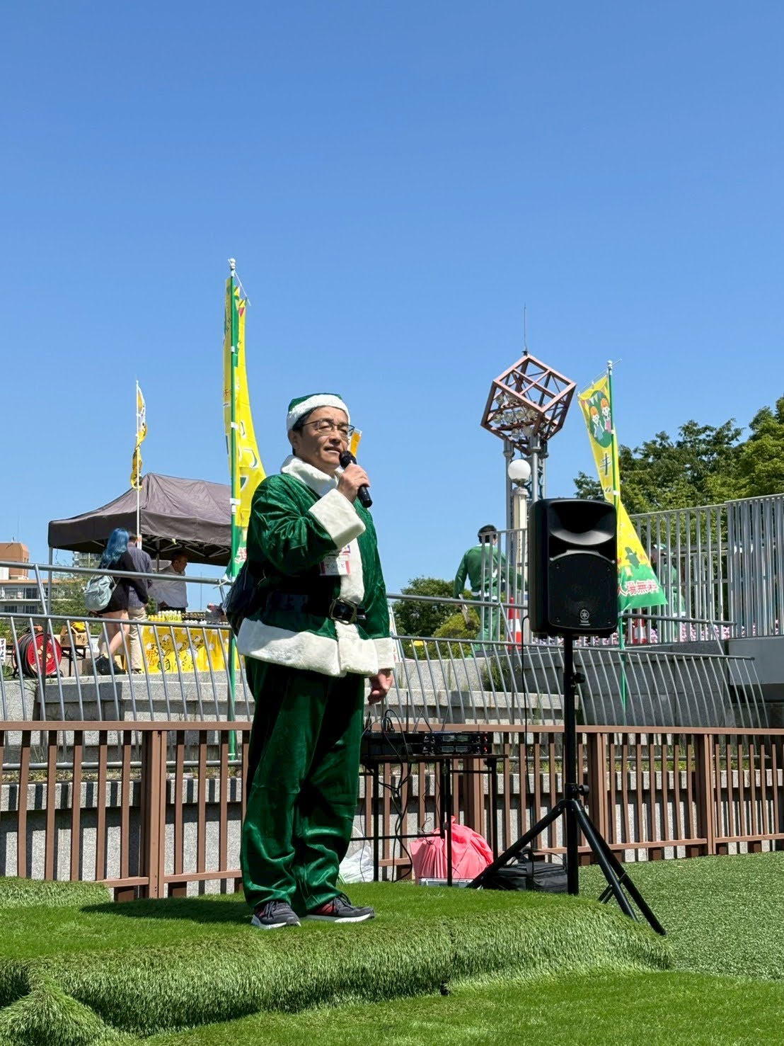 緑色のサンタクロースの格好をする寺本区長