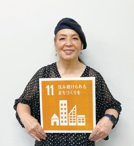 実行委員長の藤崎京子さんがSDGsの11番のボードを持っている写真