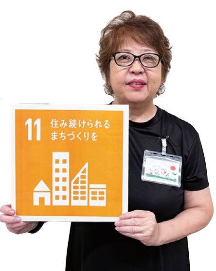 会長の小長谷明美さんがSDGsの11番のボードを持っている写真