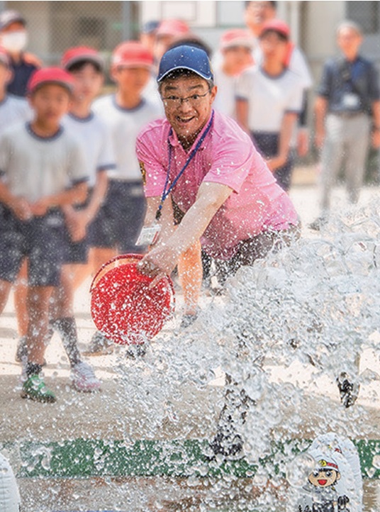 寺本区長が的めがけてバケツの水を飛ばしている様子