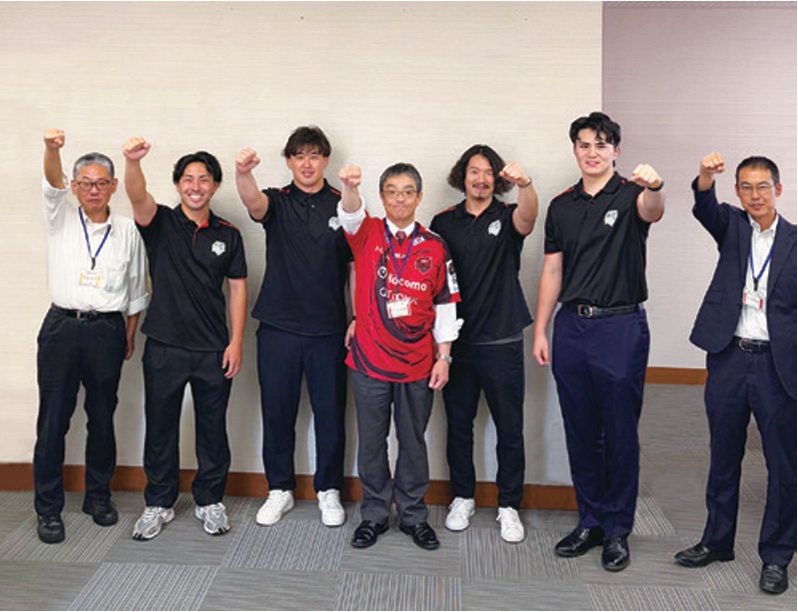 レッドハリケーンズ大阪の選手と区職員がこぶしを突き上げてポーズをきめている様子