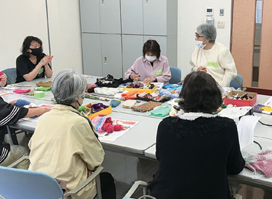 制作したマフを並べて話し合う参加者