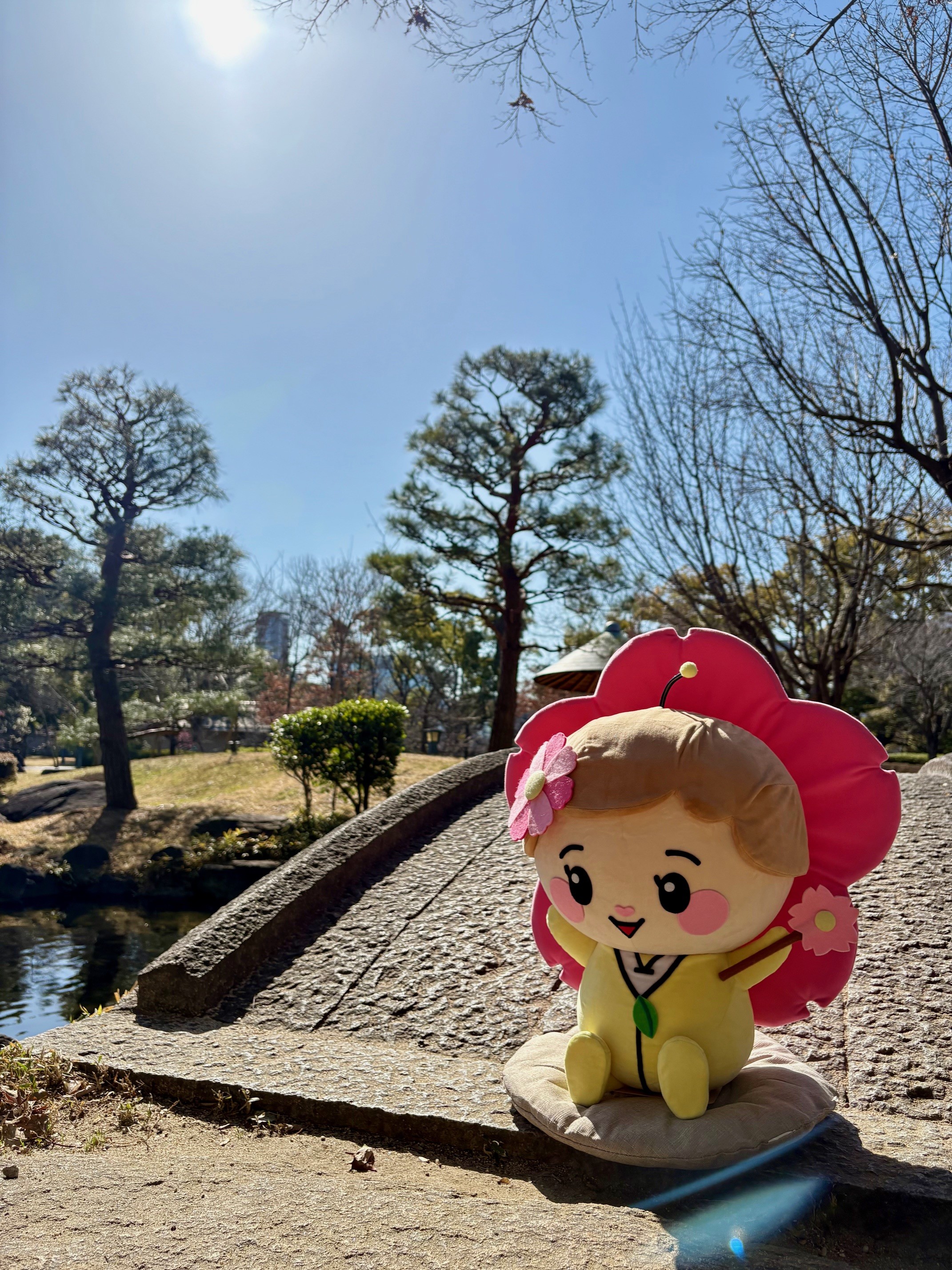 旧藤田邸庭園のかけ橋のふもとに座る都希（とっきー）のぬいぐるみ