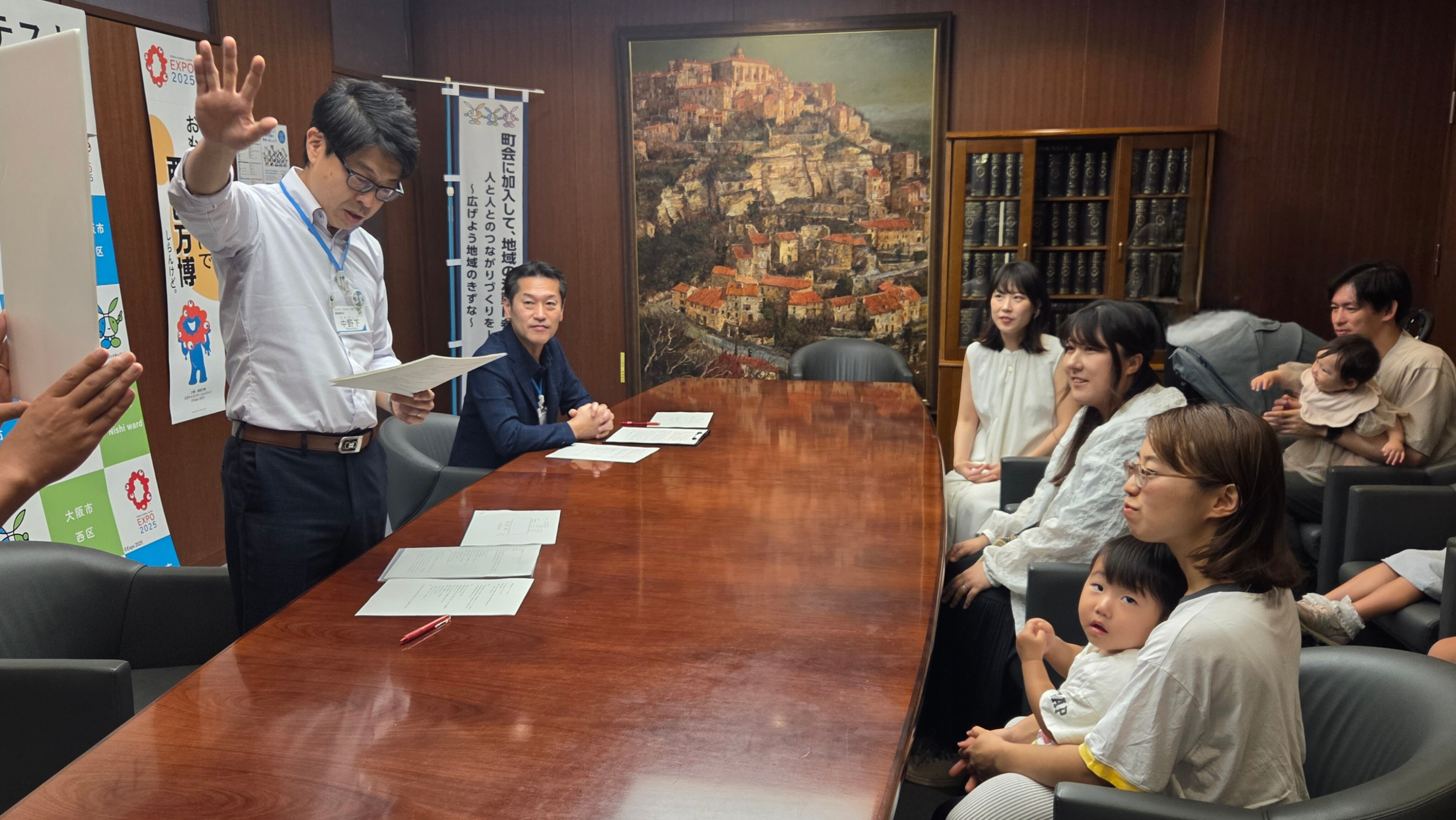 副区長と受賞者。作品パネルを見ながら審査結果の説明を受けている。