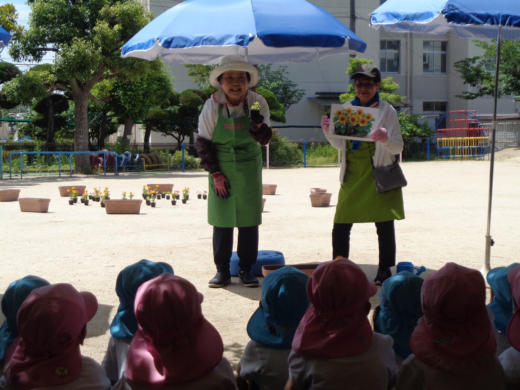 西淀川区緑化ボランティアさんが園児さんにお花の名前を教えている様子です。