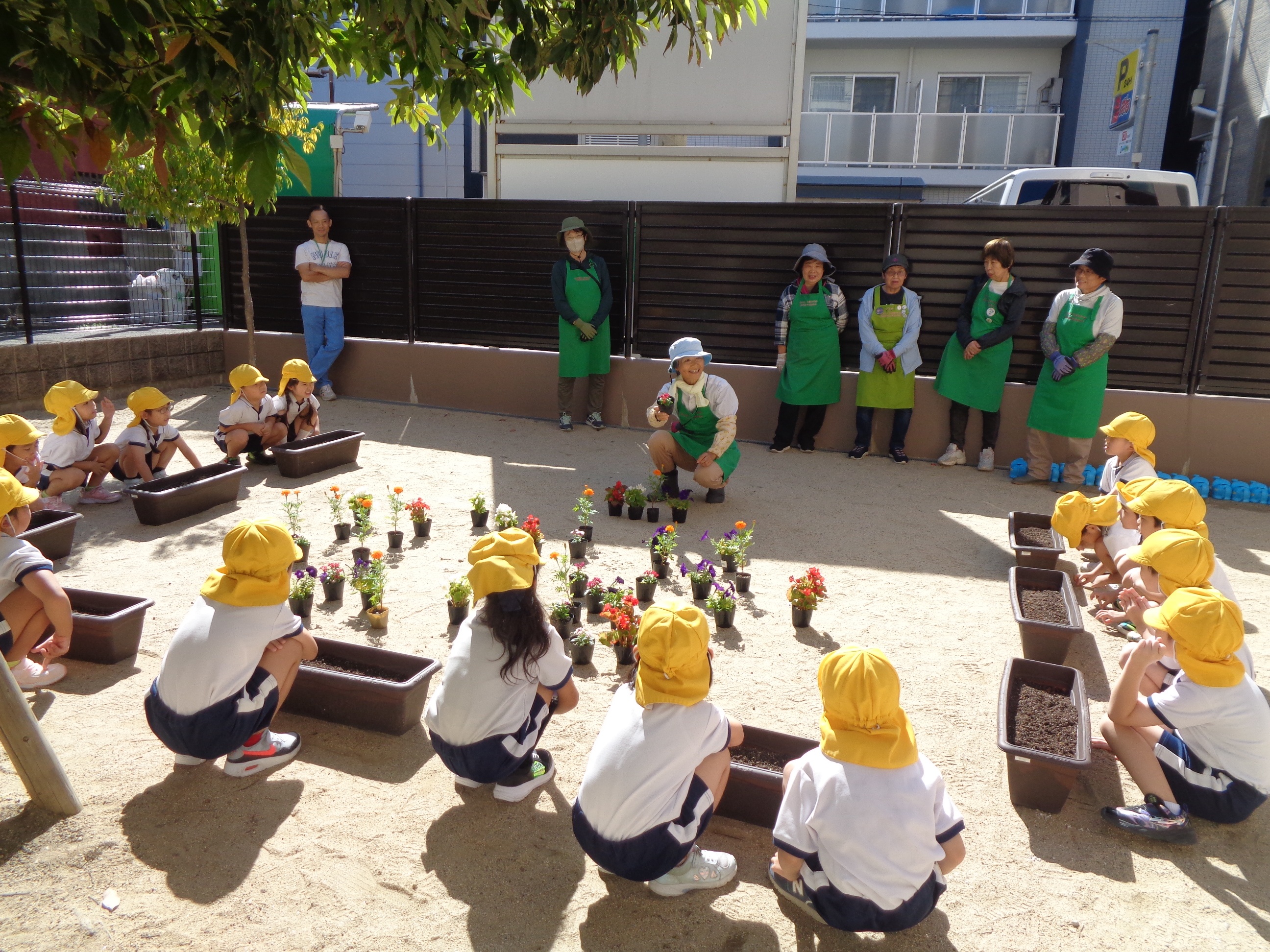 西淀川区緑化ボランティアさんが園児さんにお花の植え方を説明している様子