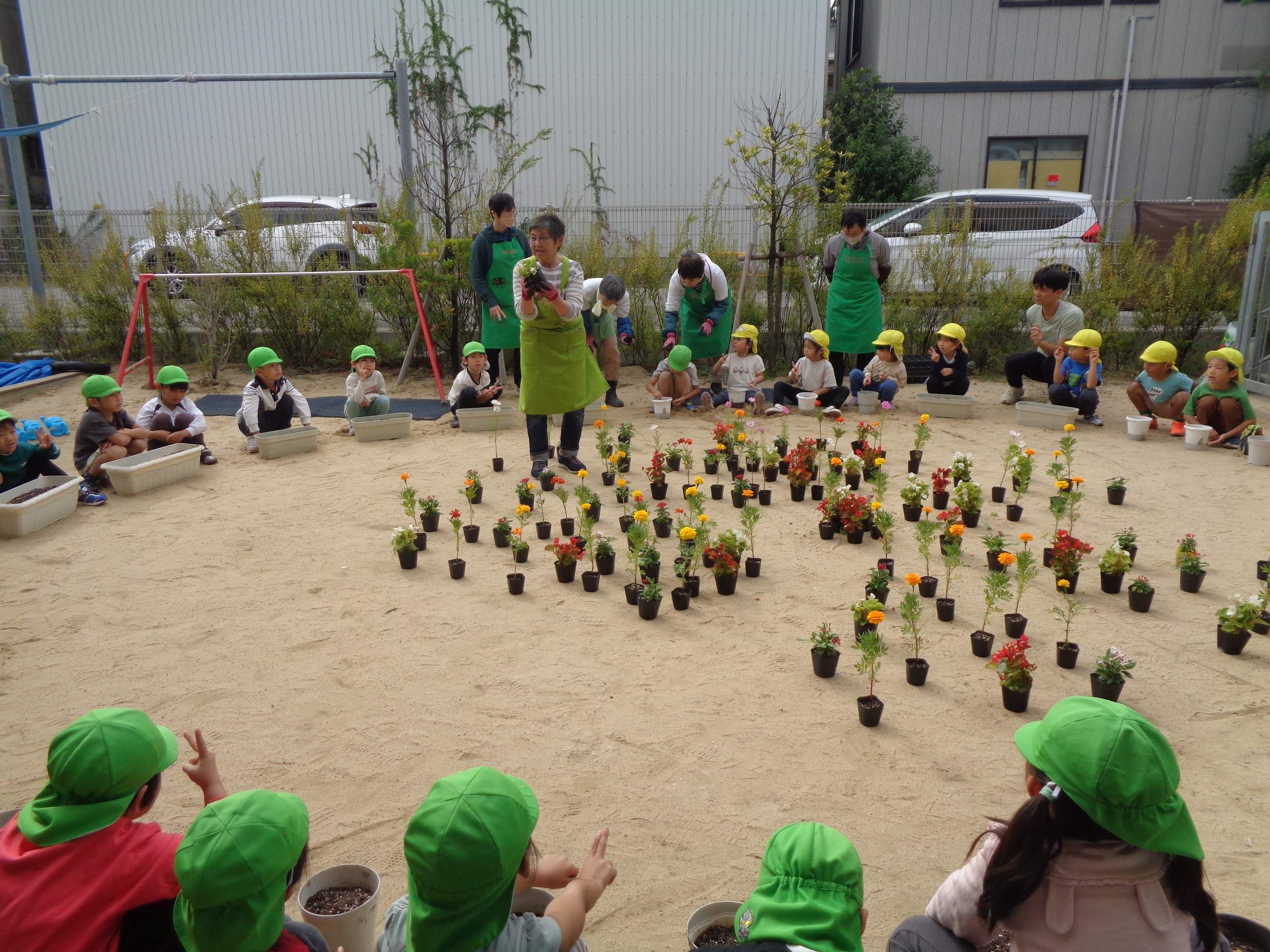 西淀川区緑化ボランティアさんが園児さんにお花の植え方を説明している様子