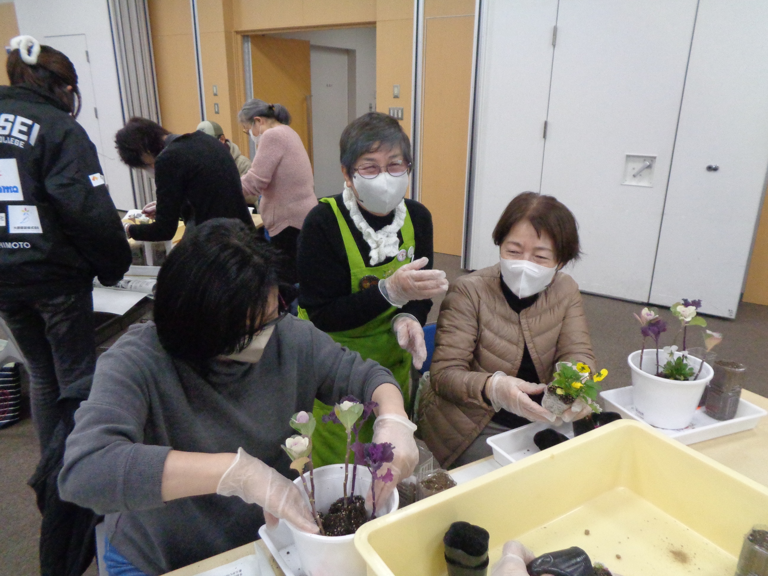 西淀川区緑化ボランティアさんが寄せ植え実習の補助をしている様子