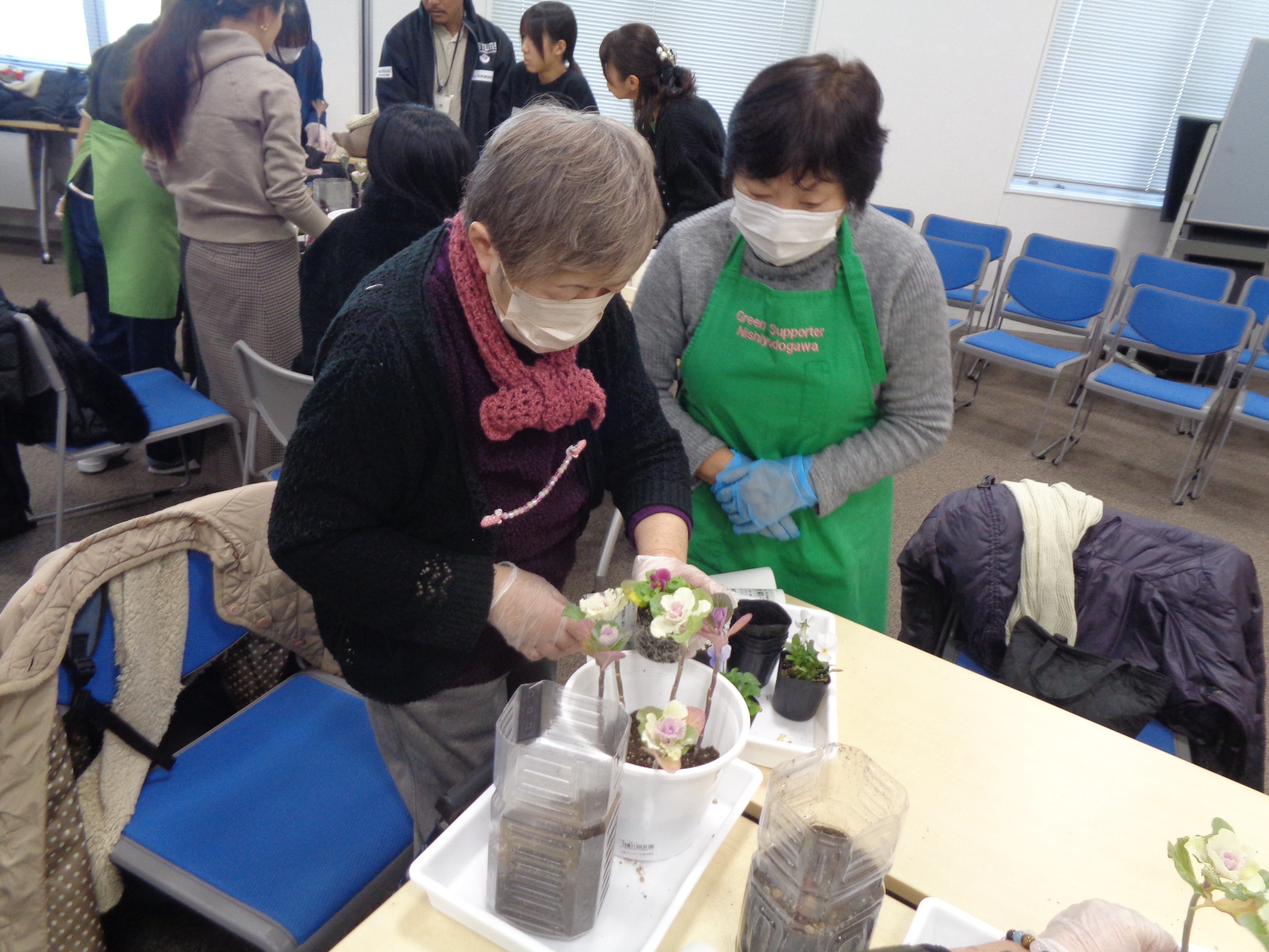 西淀川区緑化ボランティアさんが寄せ植え実習の補助をしている様子