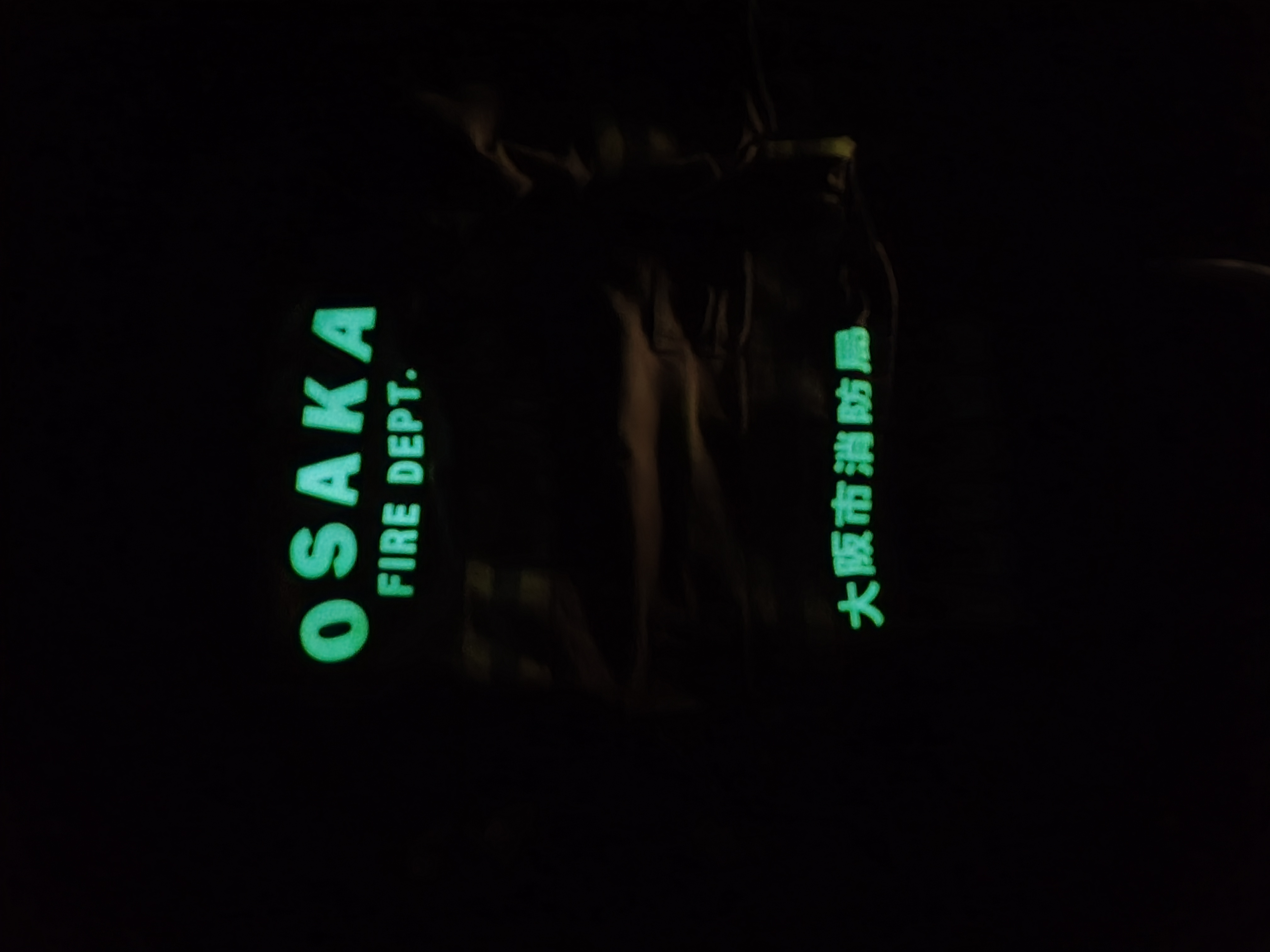 暗い場所で大阪市消防局の文字が蓄えた光を発光している写真