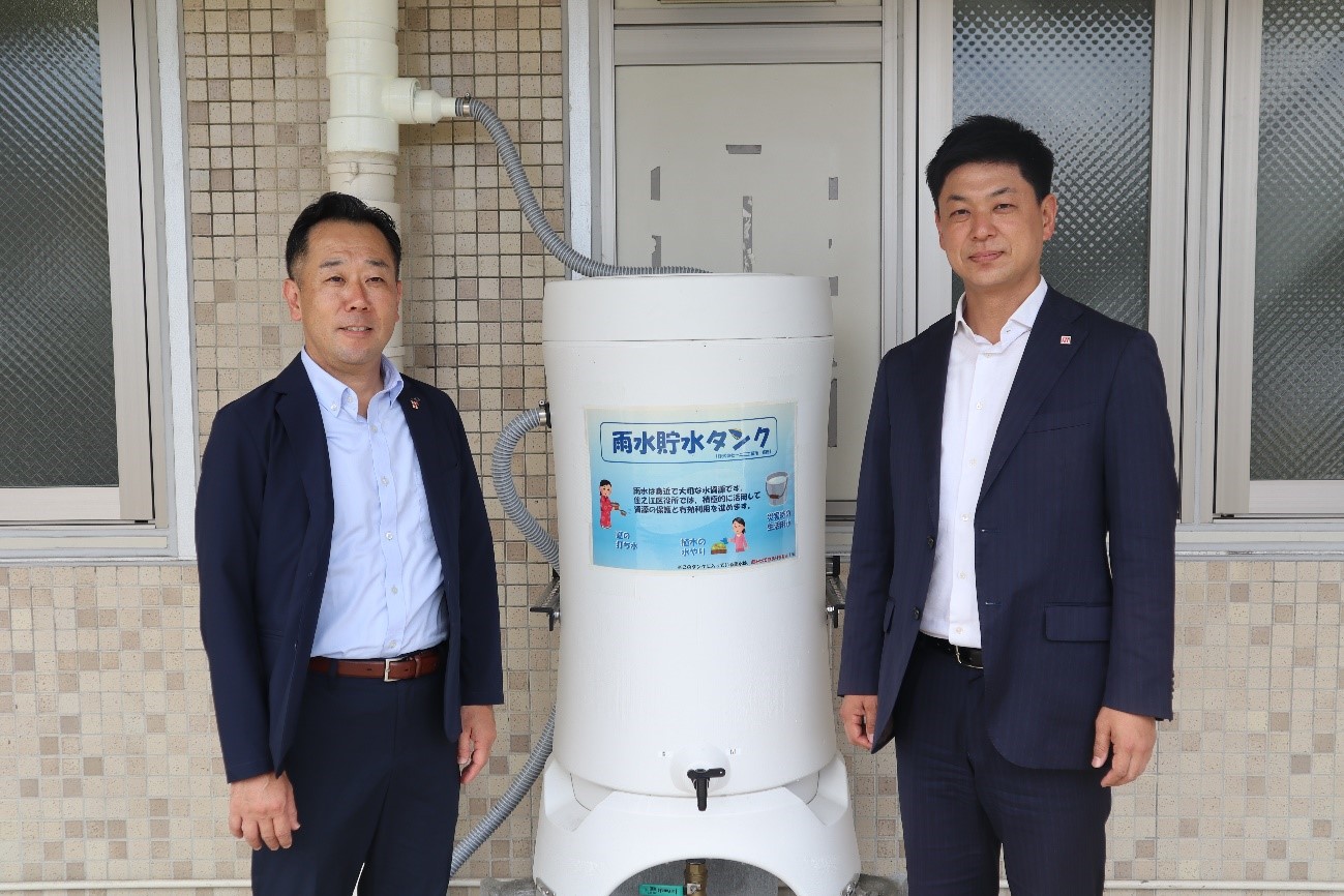 雨水貯水タンクと藤井区長と一二健夫様の写真