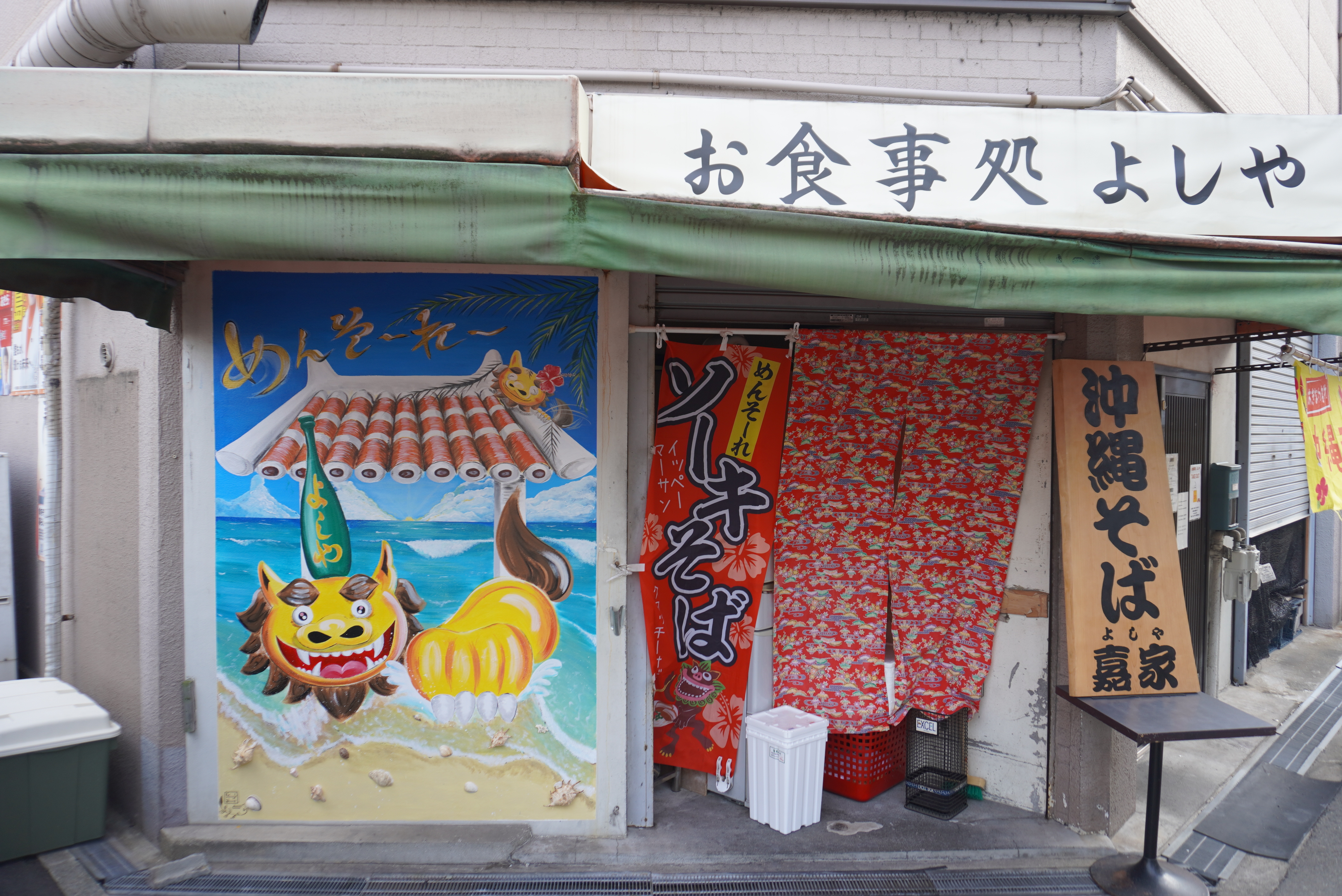 壁にシーサーが描かれている「お食事処よしや」の外観の写真