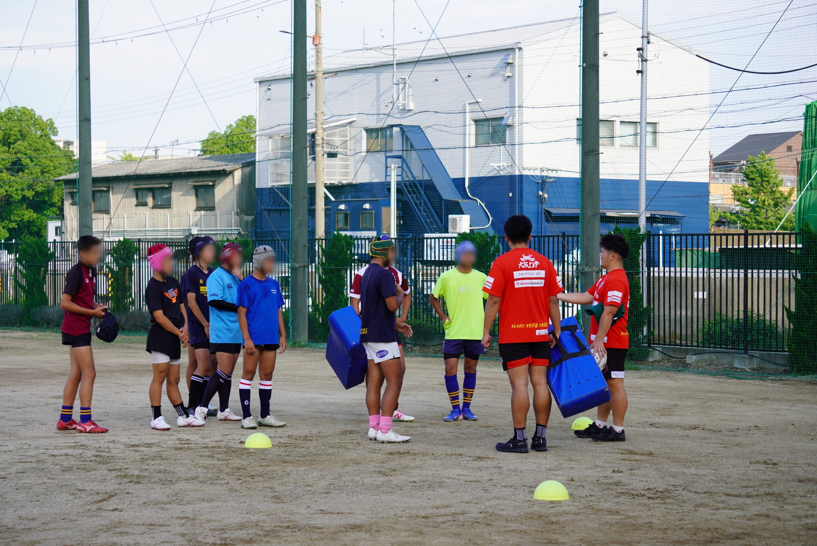 学生たちへタックル練習をの指導をしているレッドハリケーンズ大阪の選手たち