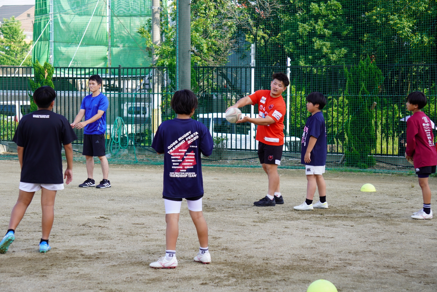パス練習をしている学生と指導しているレッドハリケーンズ大阪の選手