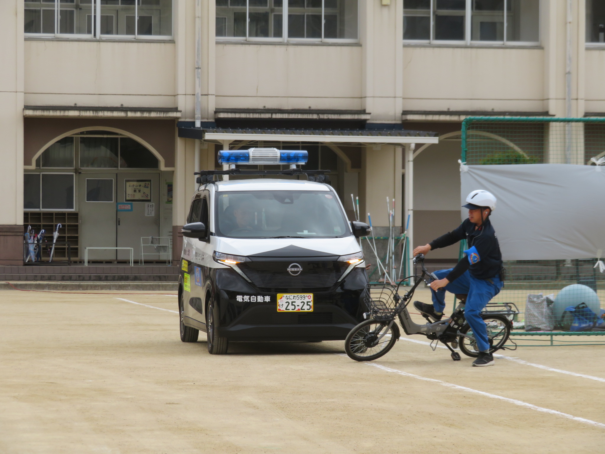小学校グランドで青パトと自転車の写真