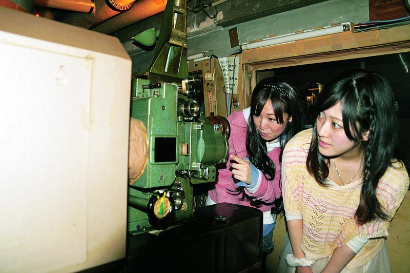 開館当初から使われている映写機を見ている佐藤さんと貞政さん