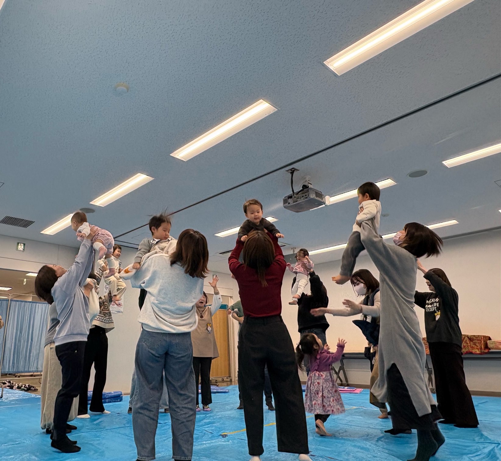 音楽に合わせて、子どもを「高い高い」している保護者