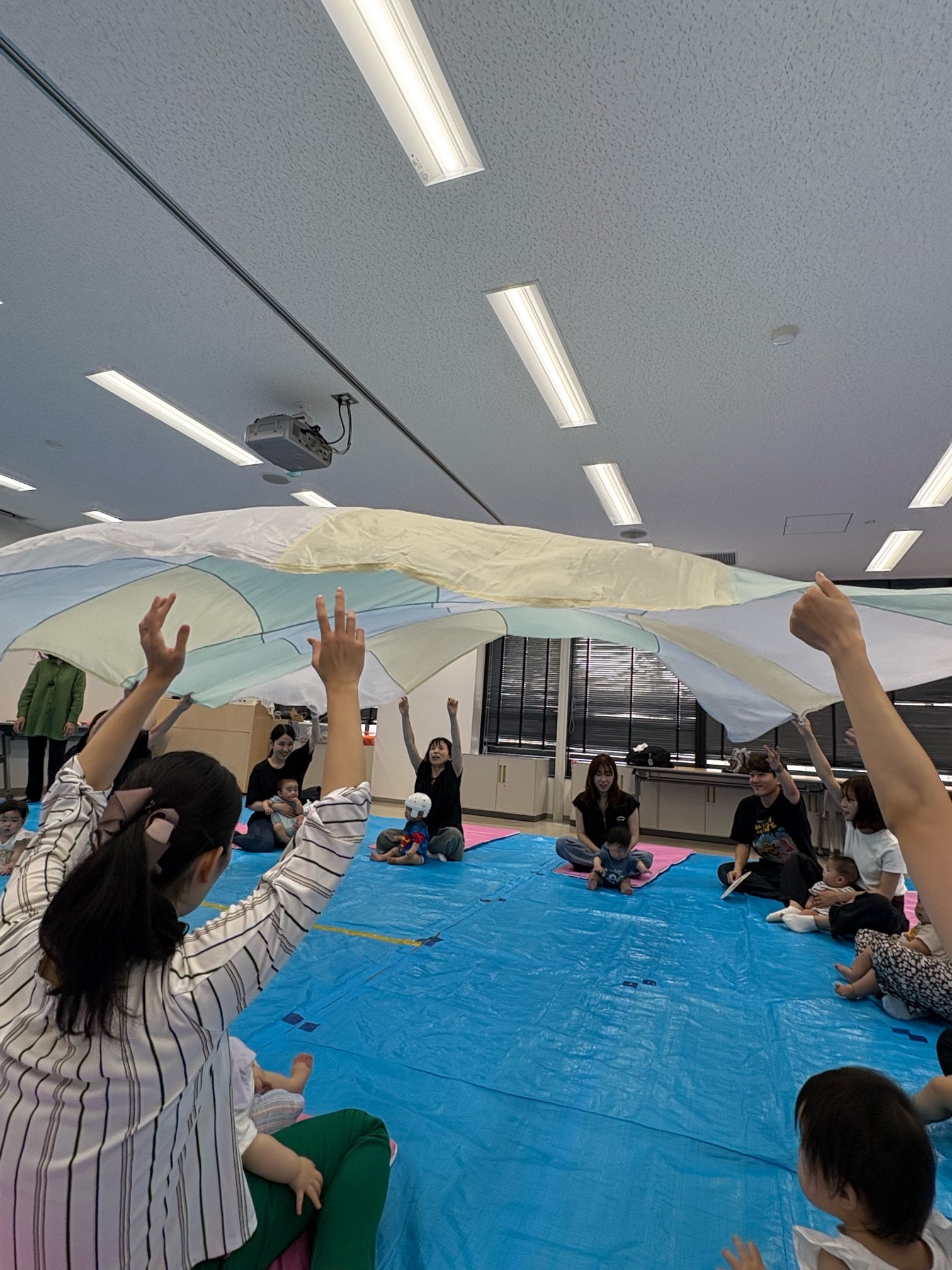 大きな布で遊ぶ親子