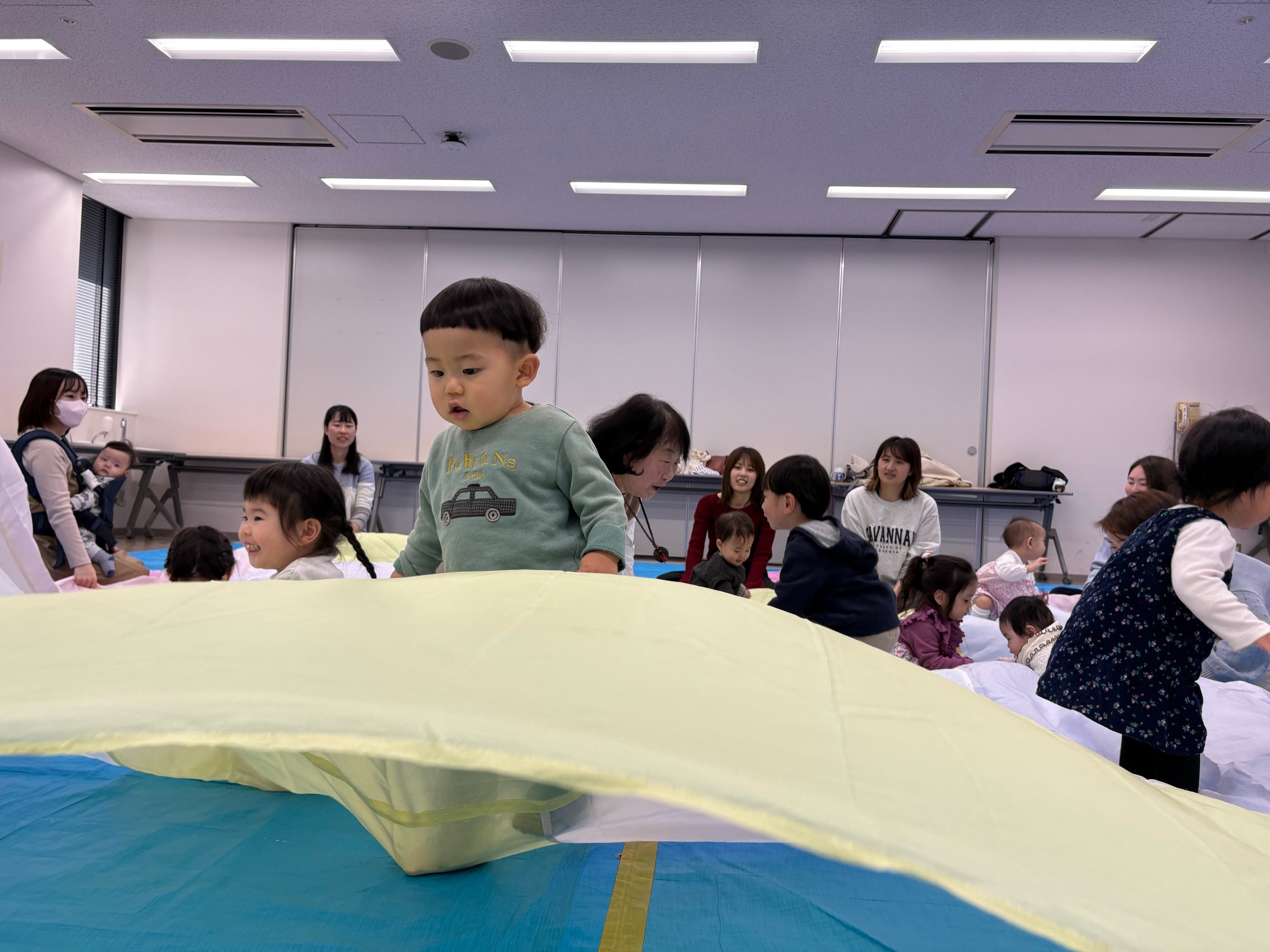 大きな布の上で遊んでいる子どもたち