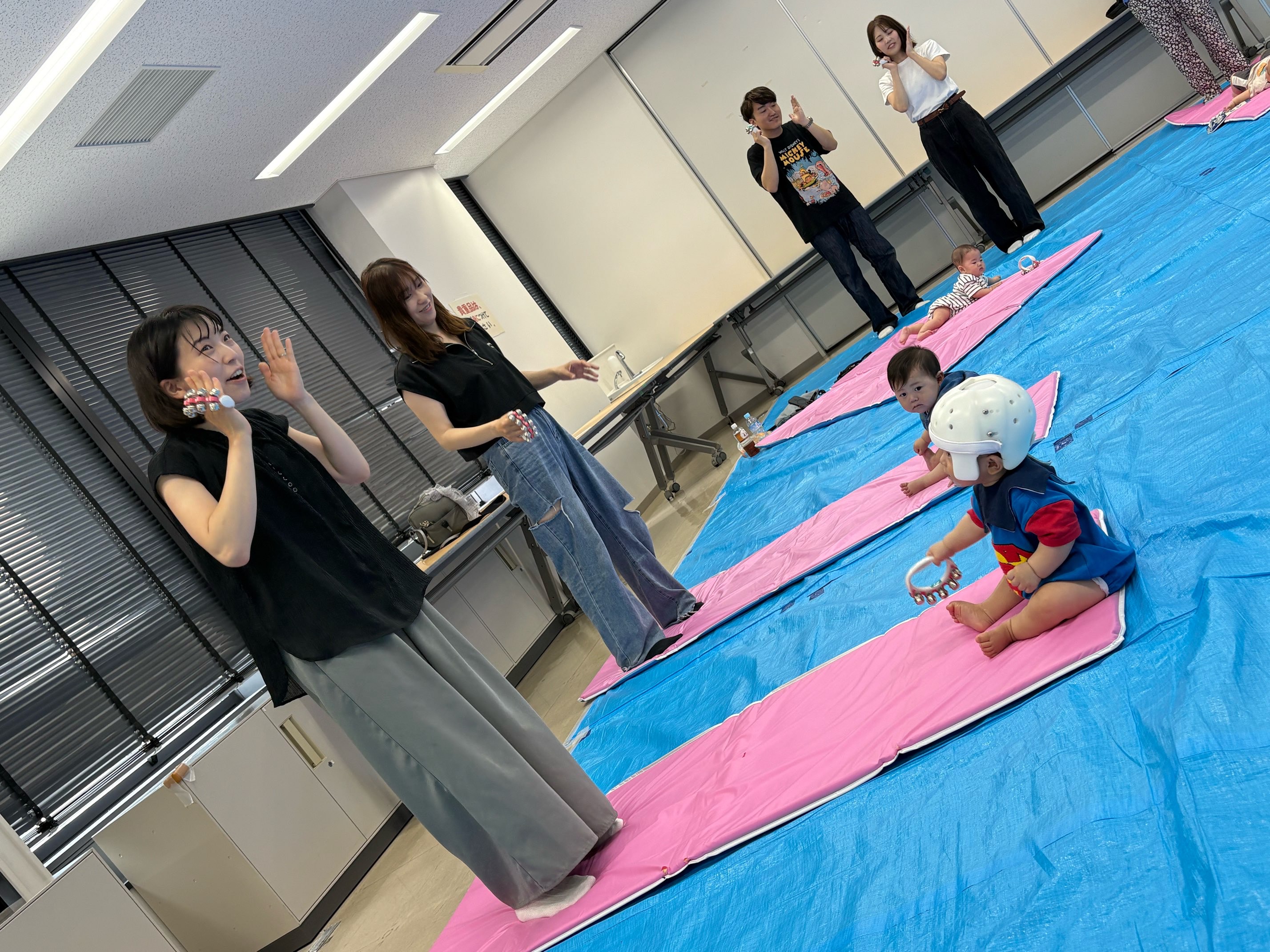保護者がダンスする様子を見ているこどもたち