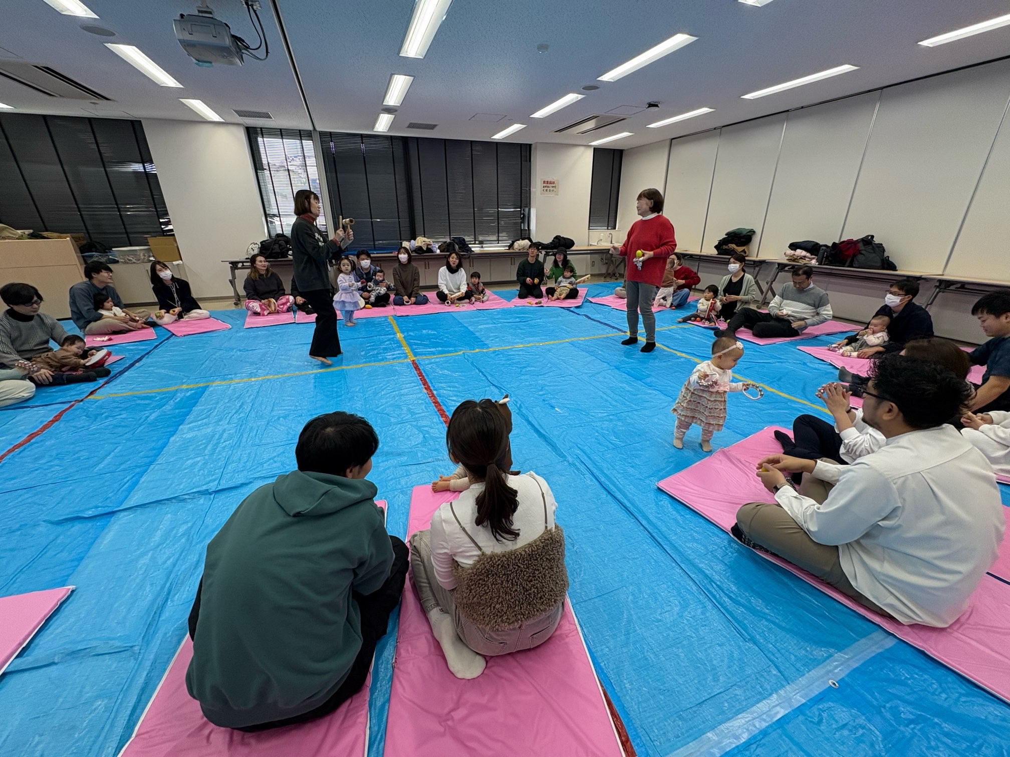 マットに座り、円になって講師の話を聞いている参加者たち