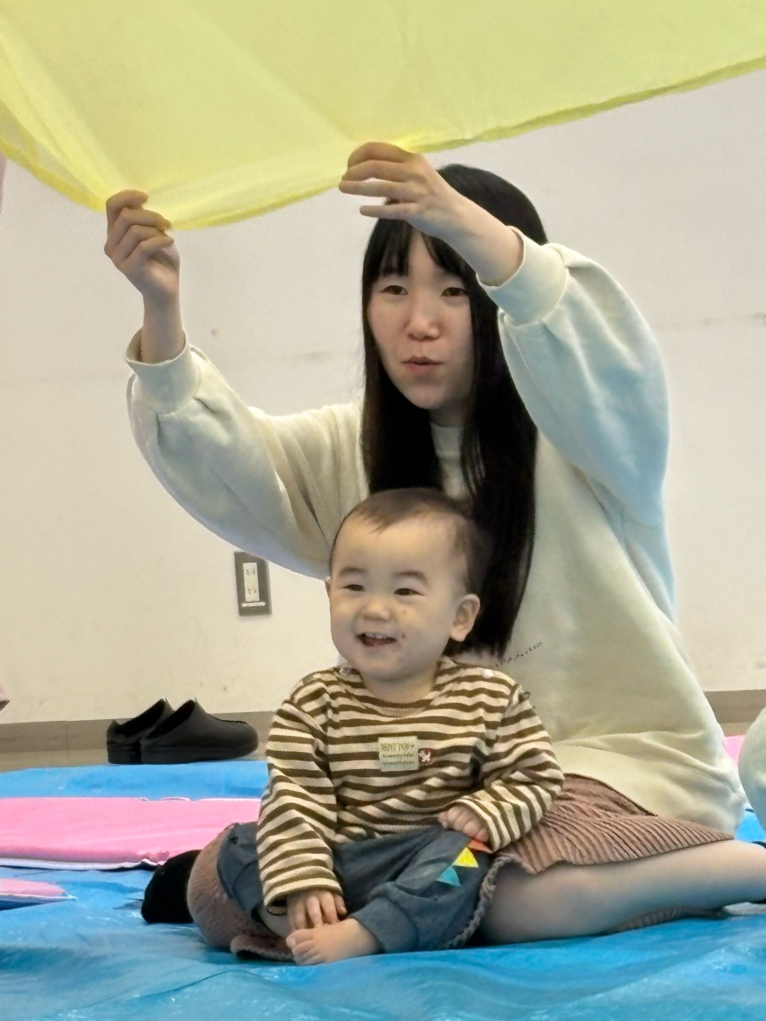 大きな布で遊んでいる親子