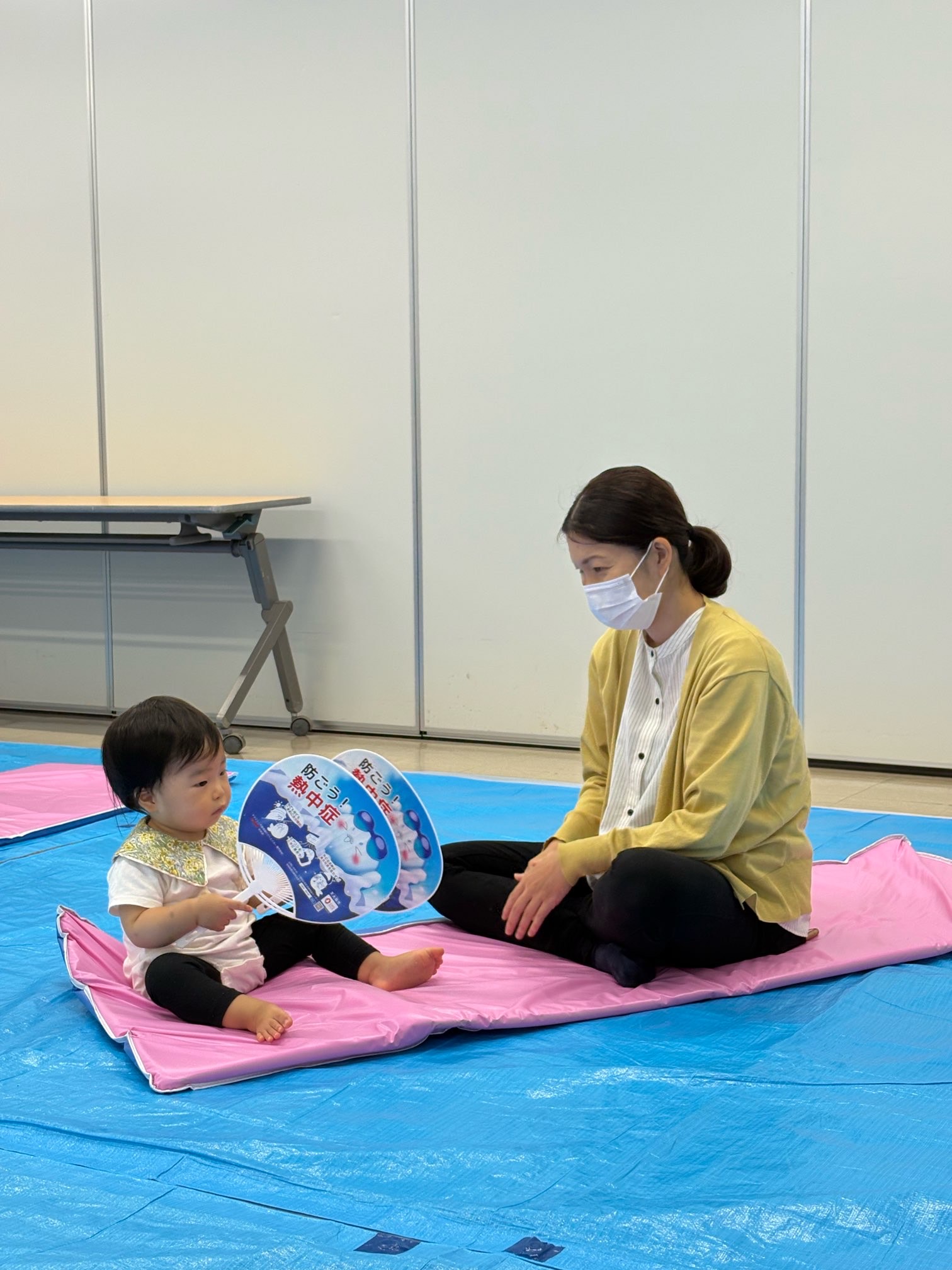 うちわを楽器に見立てて、音を鳴らし楽しんでいる親子