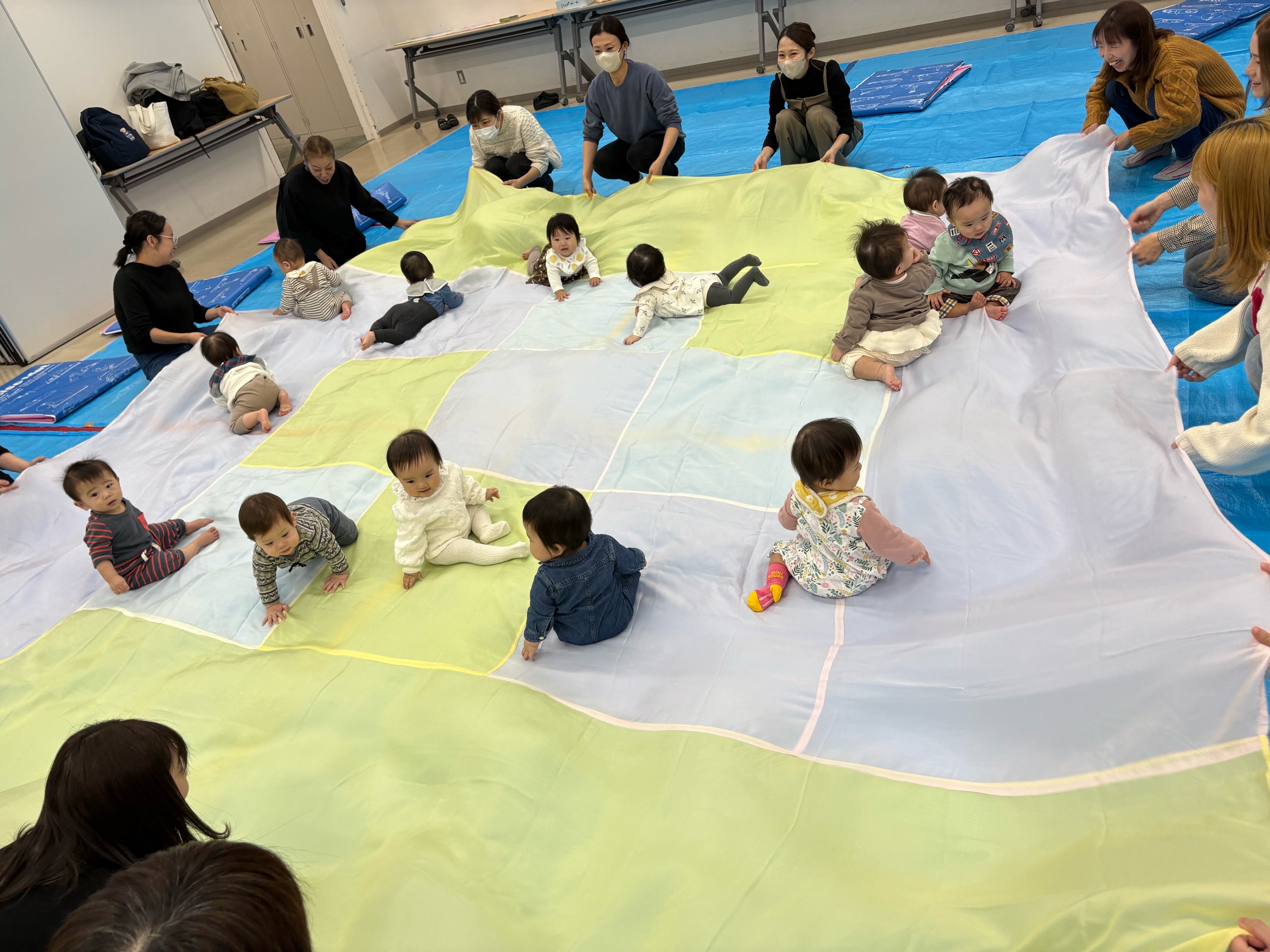 大きな布の上でたくさんの子どもたちが遊んでいる様子