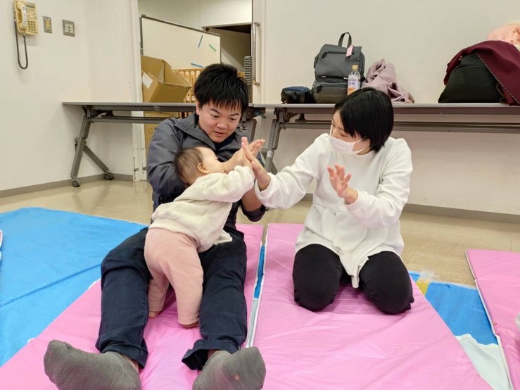 笑顔でふれあいあそびを楽しんでいる父母子の様子