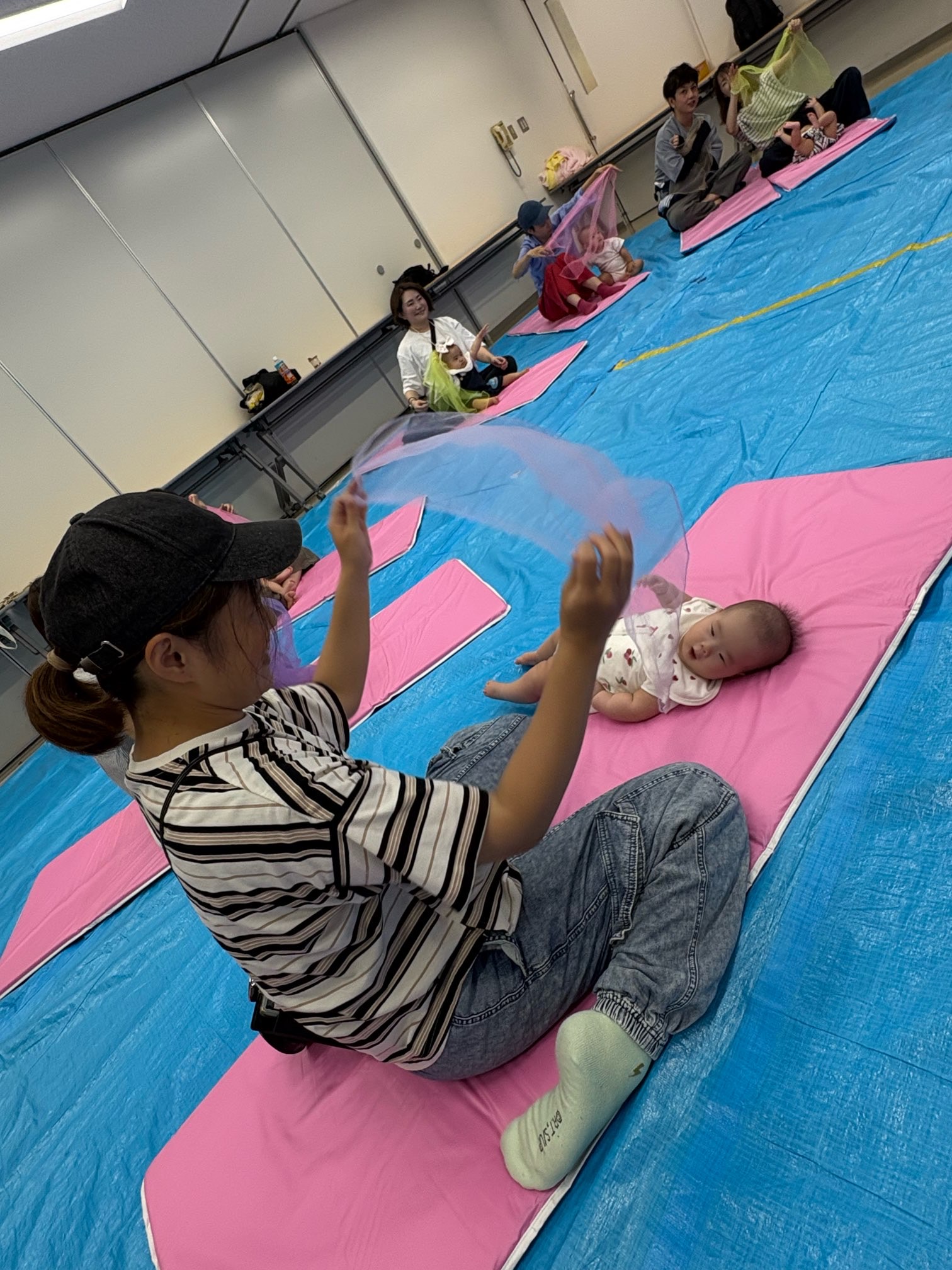 布を揺らしてあそんでいる親子