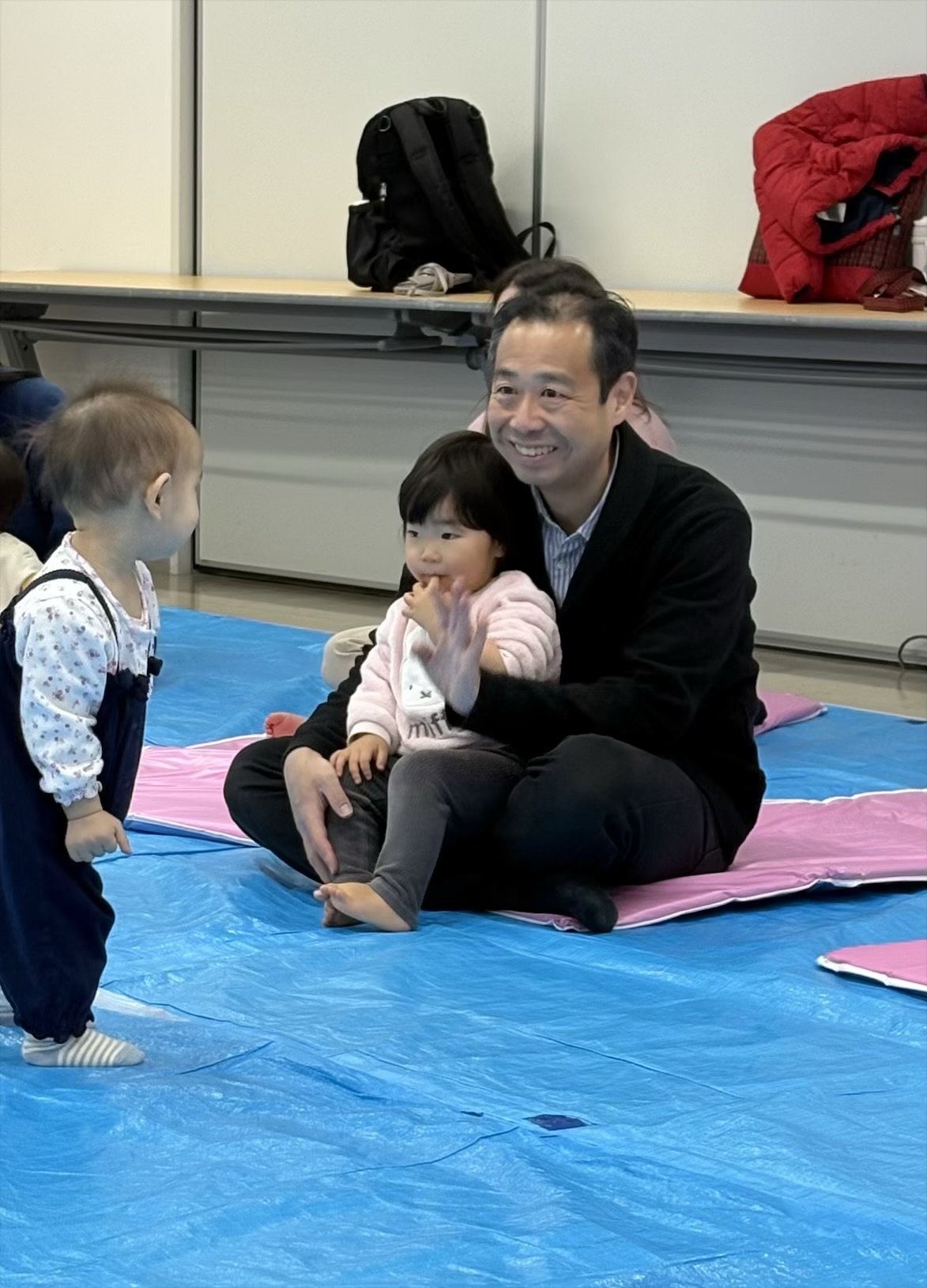 お父さんの膝に座り、ふれあいあそびを楽しむ親子