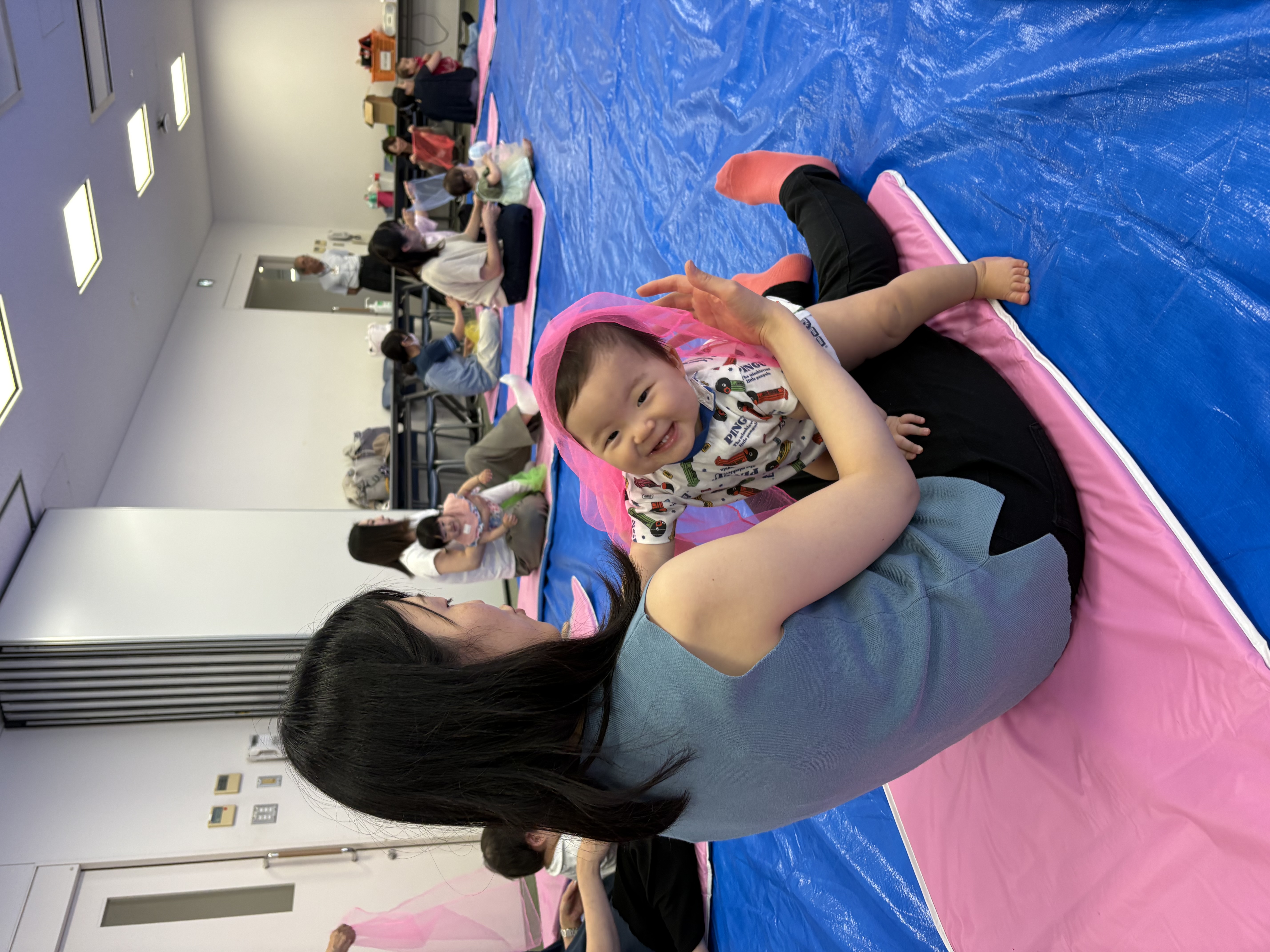子どもを膝に乗せてふれあいあそびを楽しんでいる親子